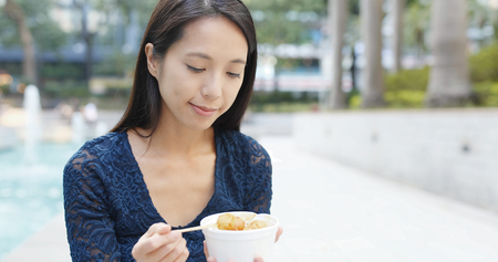 Woman eating fish ball at street, famous local food in Hong Kong の写真素材