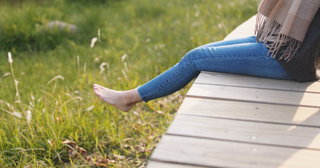 Woman sitting on wooden path under sunlight の写真素材
