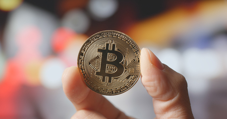 Holding Bitcoin with city background 