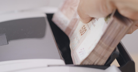 Money counter is counting paper money の写真素材