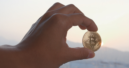 Handing holding bitcoin over the sunset timeの写真素材
