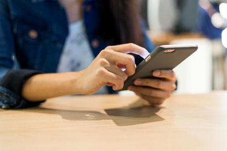 Woman using mobile phone in restaurantの写真素材