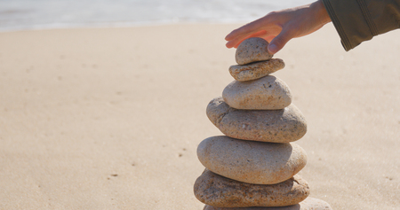 Hand putting the pebble stone on balance zen stock 