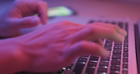Typing on notebook computer keyboard with pink lightの写真素材