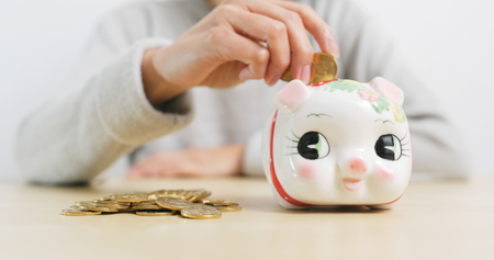 Putting golden coins into piggy bankの写真素材