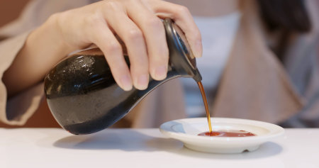 Woman putting soy sauce on plate in Japanese restaurant