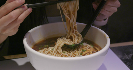 Woman eating chinese noodles in restaurant