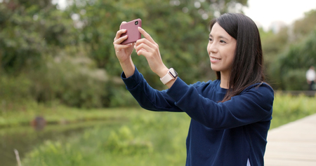 Woman taking photo with cellphone at outdoorの写真素材