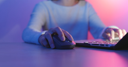 Woman Using notebook computer with blue and purple lightの写真素材