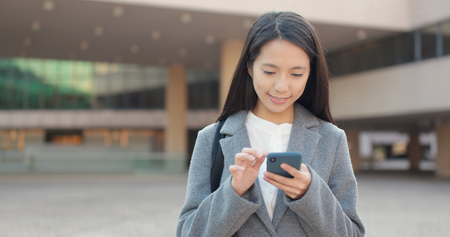 Businesswoman sending message on cellphone in cityの写真素材