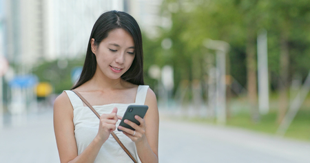 Asian Woman looks at the smart phone in cityの写真素材