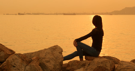 Woman sitting at the seasideの写真素材
