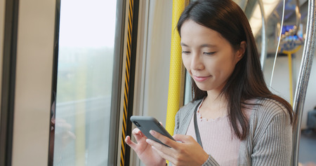 Woman using mobile phone on trainの写真素材