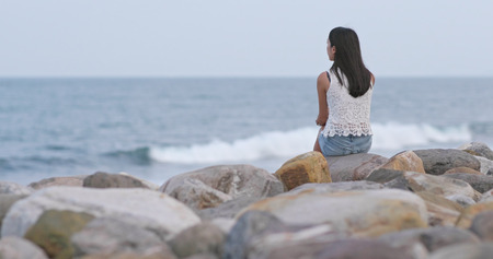 Woman sitting at the seaside and look far awayの写真素材