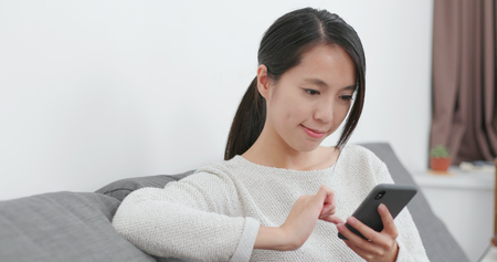 Woman use of mobile phone at homeの写真素材