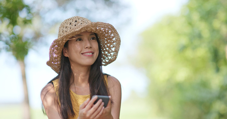 Woman wearing hat straw and taking photo by cellphone at outdoorの写真素材