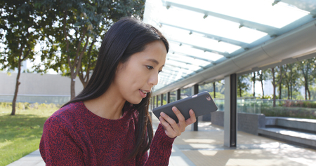 Woman using mobile phone at outdoor green parkの写真素材