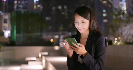 Young Businesswoman use of cellphone at nightの写真素材