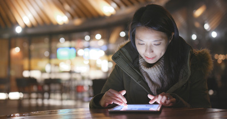 Woman using tablet computer in outdoor cafe at nightの写真素材