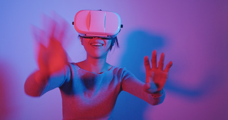 Woman watching with VR device with pink and blue lightの写真素材