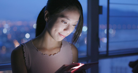 Woman use of mobile phone at home in the eveningの写真素材