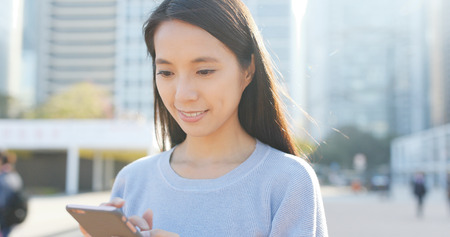 Woman reading on smart phone in cityの写真素材