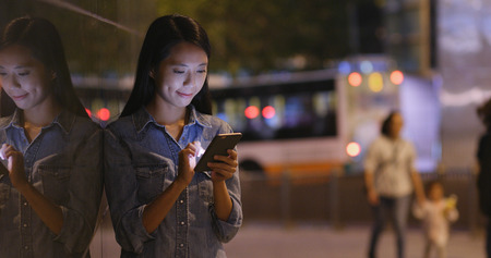 Woman working on mobile phone at nightの写真素材