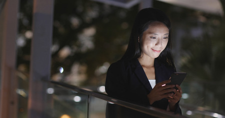 Businesswoman use cellphone at nightの写真素材