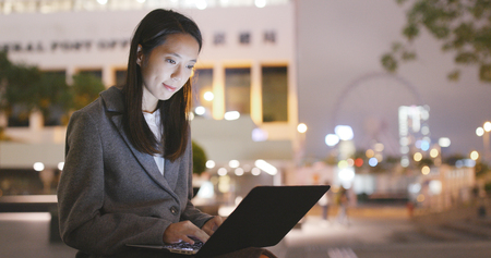 Businesswoman use of laptop computer at nightの写真素材