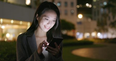 Business woman use of smart phone in city at nightの写真素材