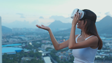 Woman watching though VR device at sunsetの写真素材