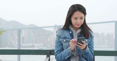 Woman use of mobile phone at outdoorの素材 [FY310111844414]