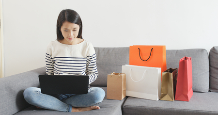 Woman shopping online on notebook computer at homeの写真素材