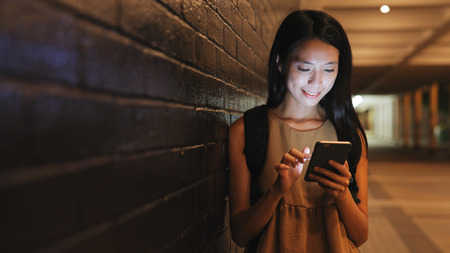 Woman backpacker using mobile phone in cityの写真素材