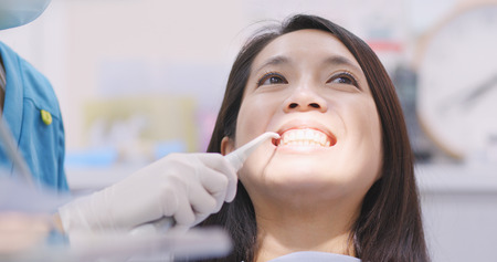 Woman dentist working at her patients teethの写真素材