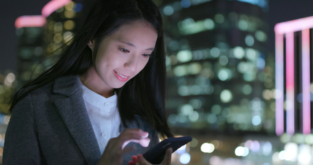Business woman work on mobile phone at nightの写真素材