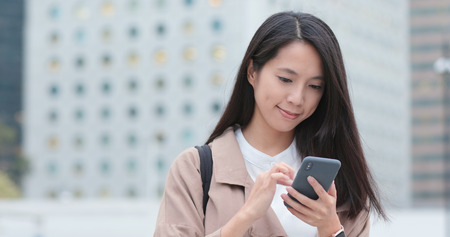 Woman reading on cellphone at outdoorの写真素材