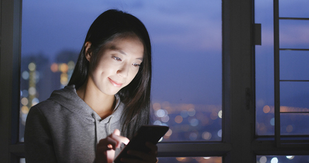 Woman watching in mobile phone at nightの写真素材