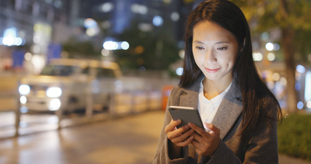 Business woman hold with mobile phone at nightの写真素材