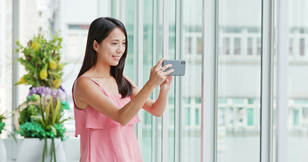 Woman taking photo on cellphone inside shopping mallの写真素材