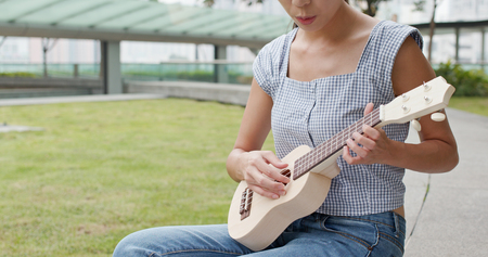 Woman play ukulele at parkの写真素材