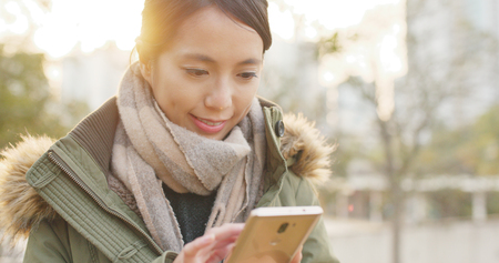 Woman use of smart phone under sunsetの写真素材