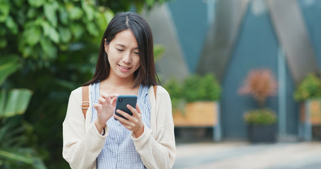 Woman using mobile phone with the background of green plantの写真素材