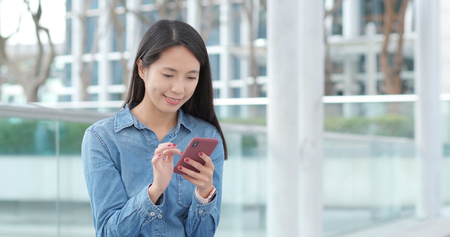 Asian woman using mobile phone in cityの写真素材