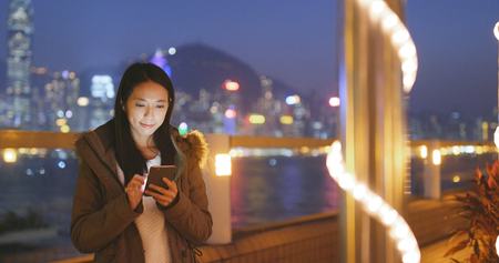 Woman using mobile phone in the city at nightの写真素材