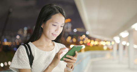 Woman surfing on cellphone at nightの写真素材