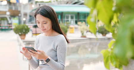Woman using smart phone to check mobile app at outdoorの写真素材