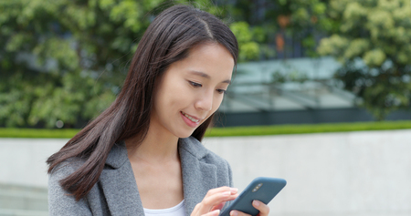 Business woman sending sms on cellphoneの写真素材
