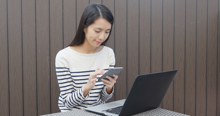 Woman using cellphone and laptopの写真素材