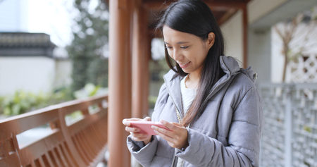 Asian woman play game on cellphone at gardenの写真素材